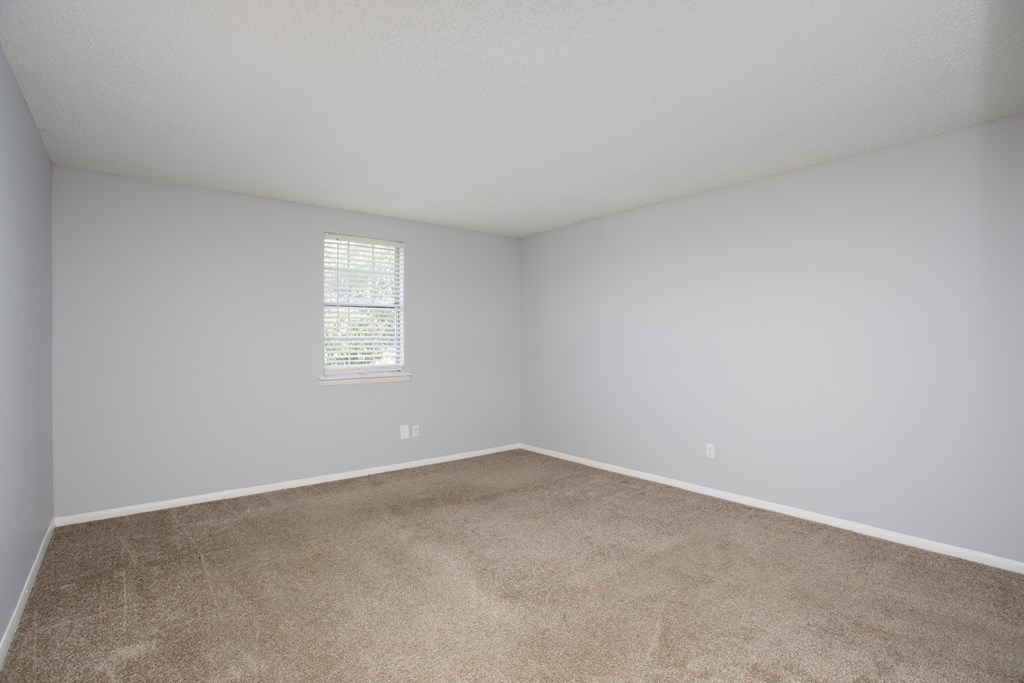 a bedroom with a carpeted floor and a small window