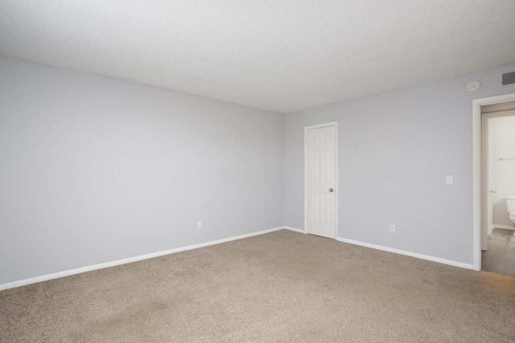 a bedroom with a carpeted floor and a white door