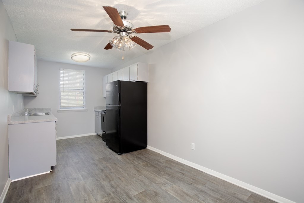 a bedroom with a ceiling fan and a kitchen in the background