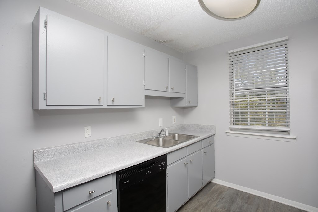 a kitchen with white cabinets and a black dishwasher
