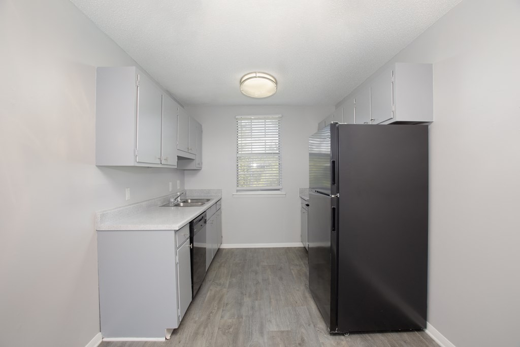 a kitchen with white cabinets and a black refrigerator
