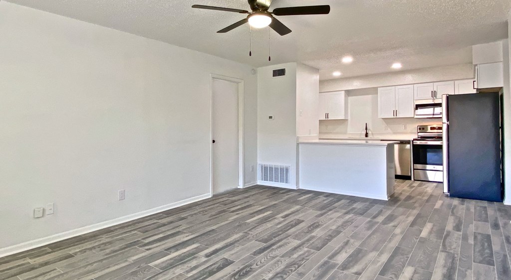 an empty living room and kitchen with a ceiling fan