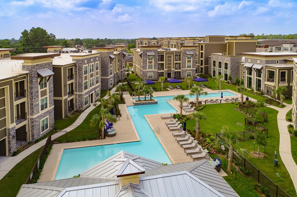 an aerial view of a large resort style pool with lounge chairs and grassy areas