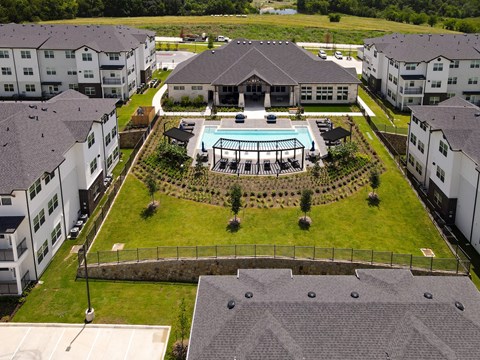 A large white building with a pool in the middle of a grassy area.
