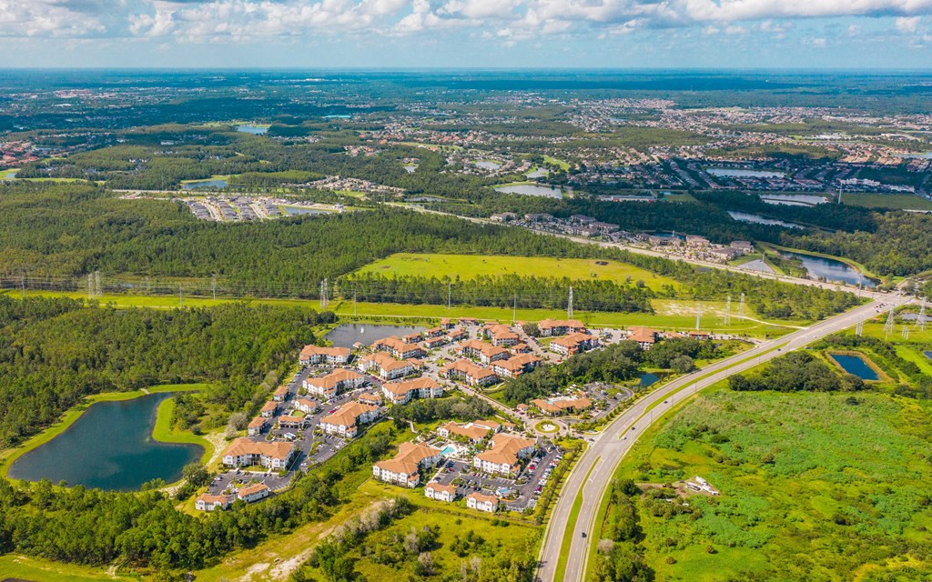 A bird's eye view of a residential area with a lake and a road.