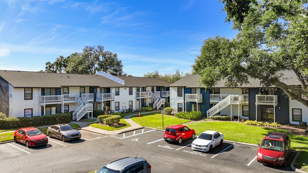an exterior view of an apartment building with cars parked in a parking lot