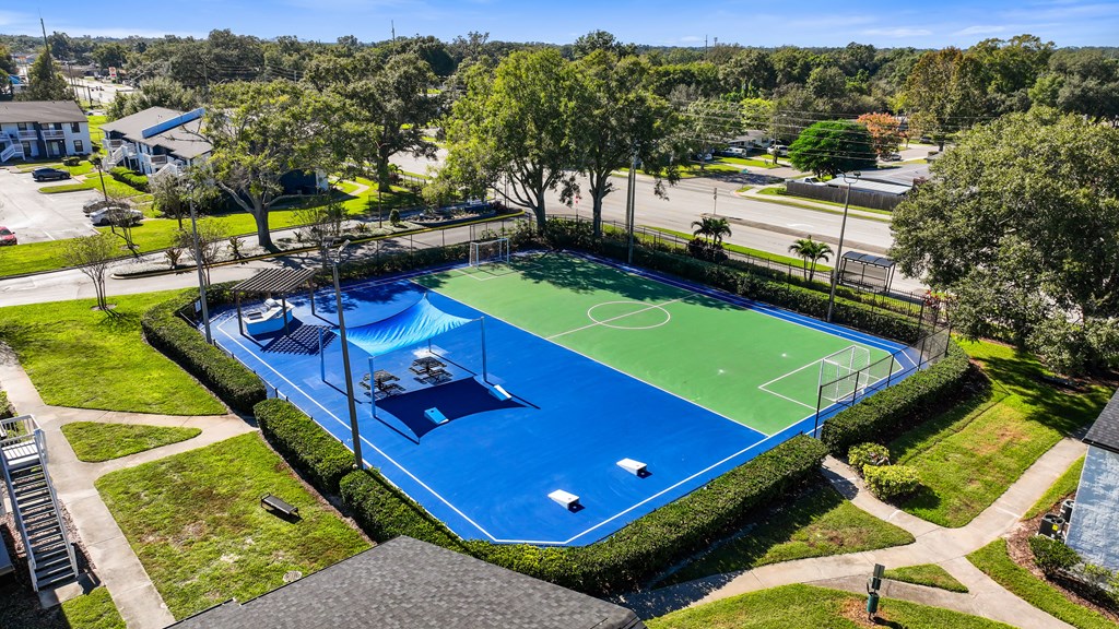 an aerial view of a blue and green basketball court in a park with trees