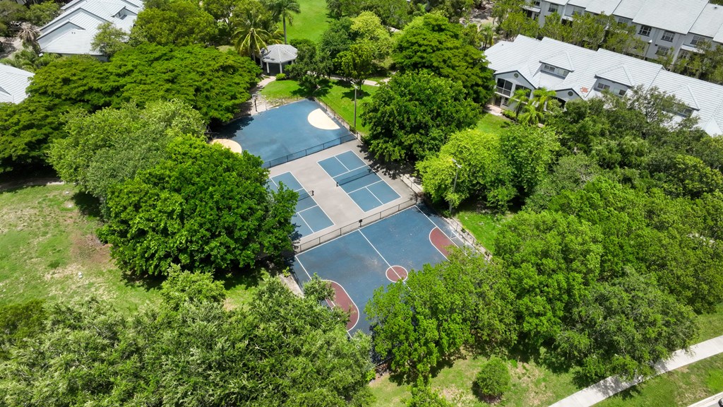 an aerial view of a tennis court and a house with trees