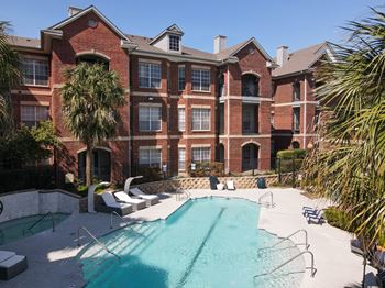 A large brick building with a pool in front.