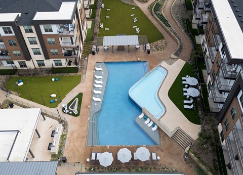 A large swimming pool surrounded by a grassy area and a concrete walkway.