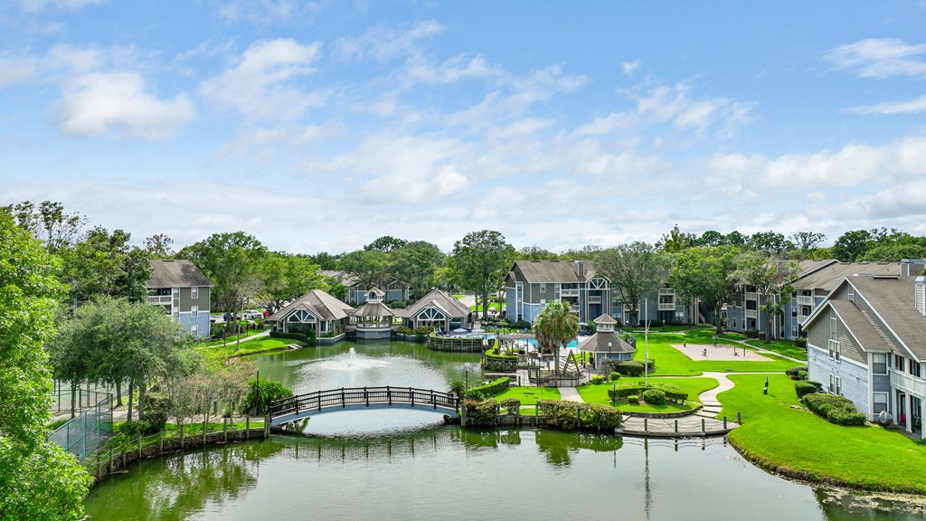 an aerial view of a lake with a bridge and houses in the background
