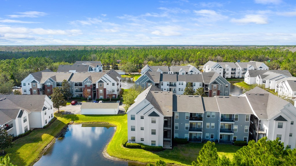 an aerial view of an apartment complex with a lake and trees