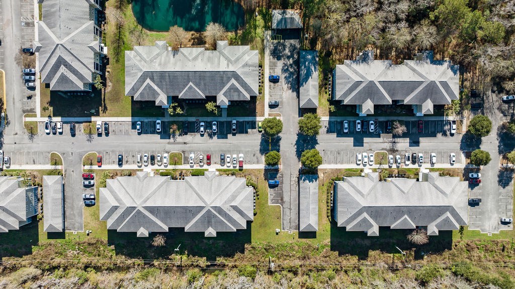 A bird's eye view of a parking lot with cars and buildings.