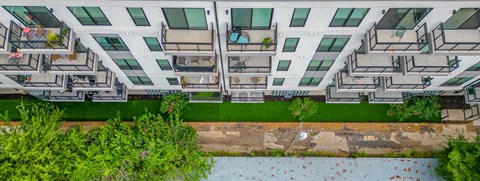 an aerial view of an apartment building with green grass and trees in front of it