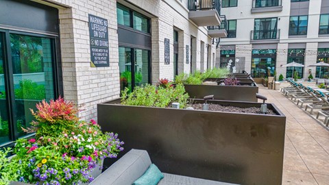 a seating area with a bench and flowers in front of a building