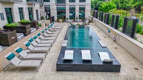 a pool with lounge chairs and a building in the background