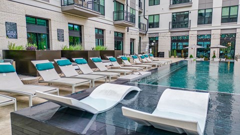 a pool with lounge chairs and a building in the background