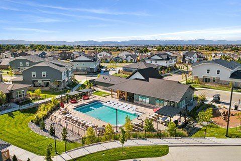 A large swimming pool surrounded by a black fence and a grassy area with a few trees.