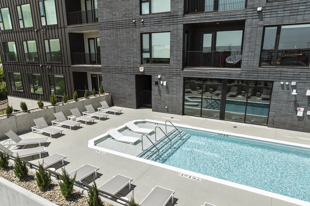 a swimming pool in front of a building with lounge chairs