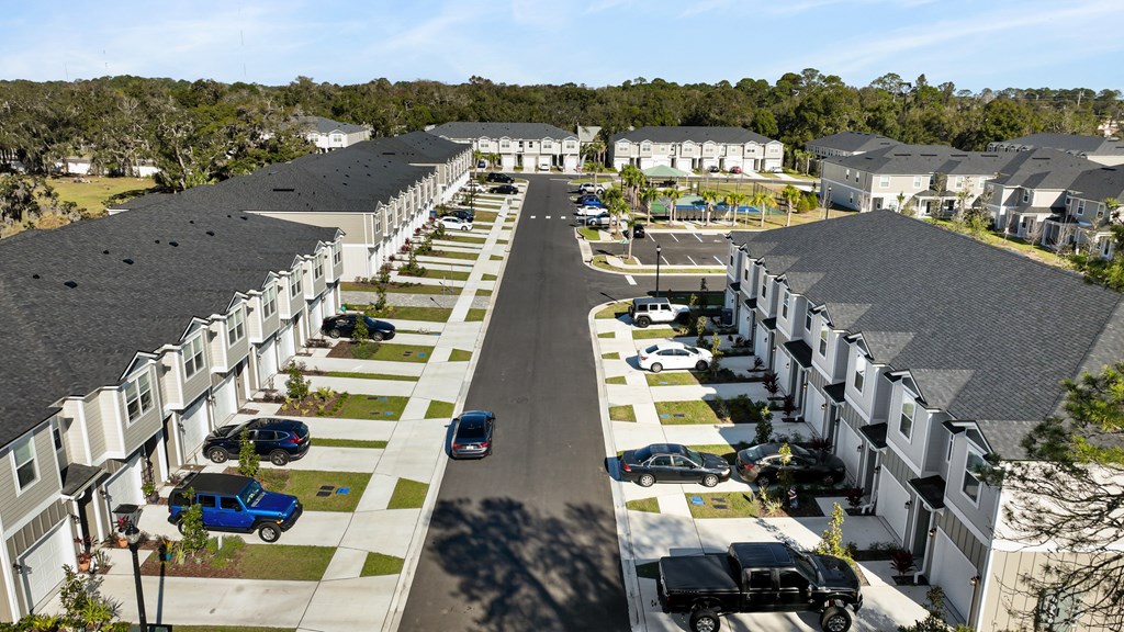 A street view of a residential area with houses on both sides and cars parked in the driveways.
