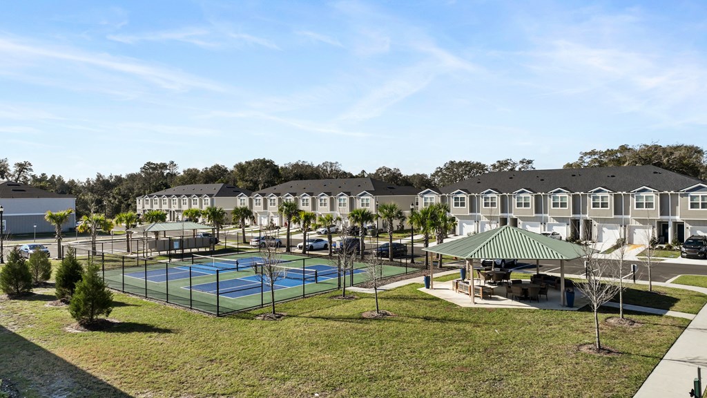 A tennis court is surrounded by houses and trees.