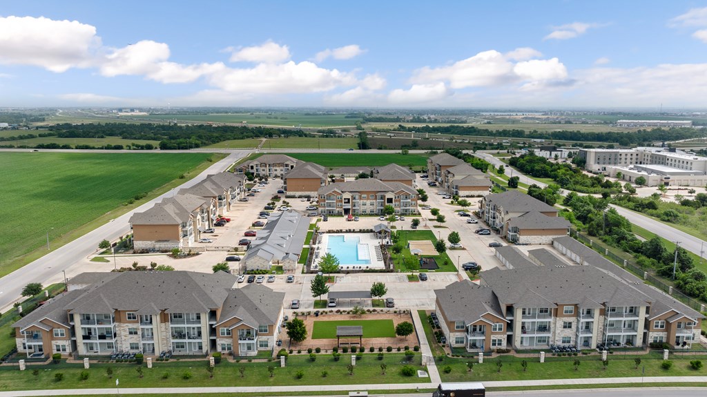 A large apartment complex with a swimming pool in the middle.