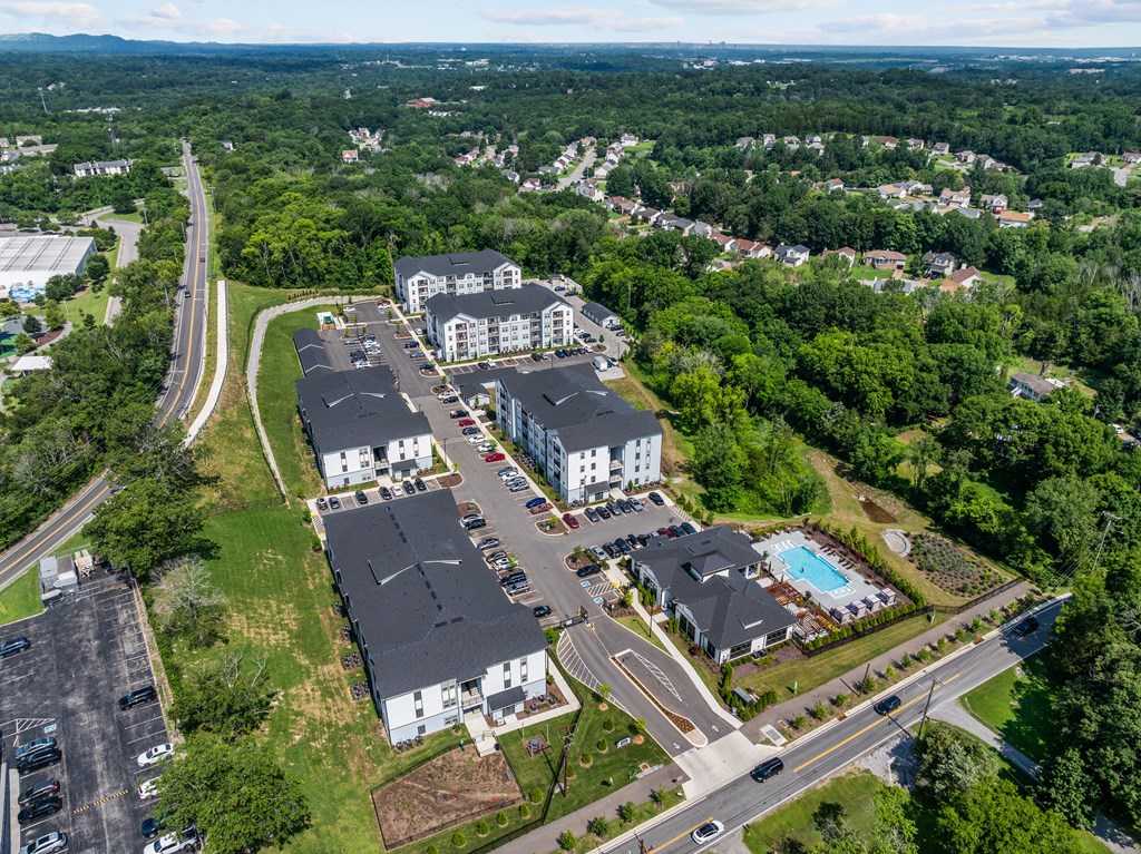 A bird's eye view of a residential area with houses, roads, and a parking lot.