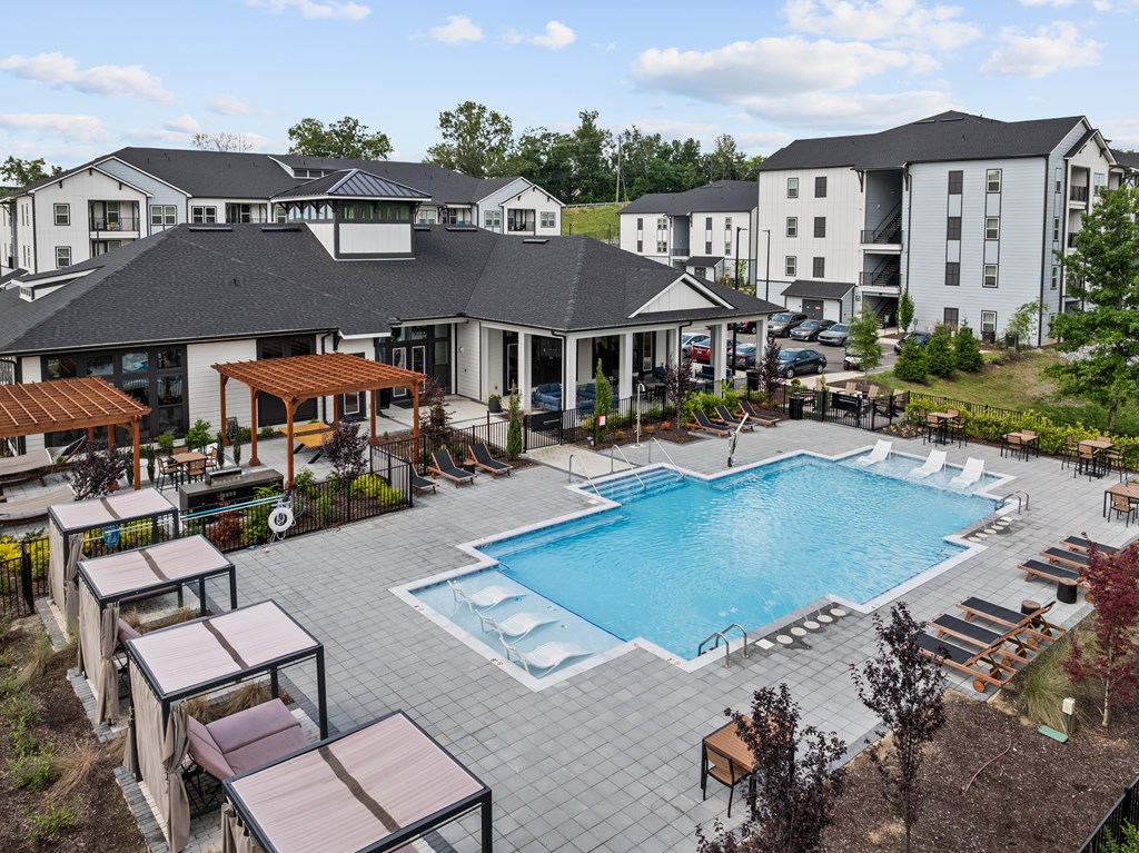 A large outdoor swimming pool surrounded by lounge chairs and umbrellas.