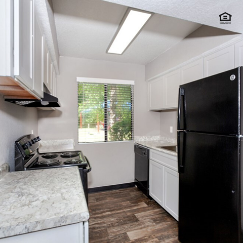 a kitchen with a black refrigerator and a window