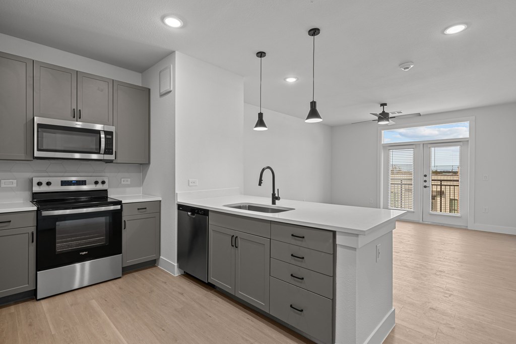 A modern kitchen with a stainless steel oven and microwave, a sink with a faucet, and a countertop with drawers.