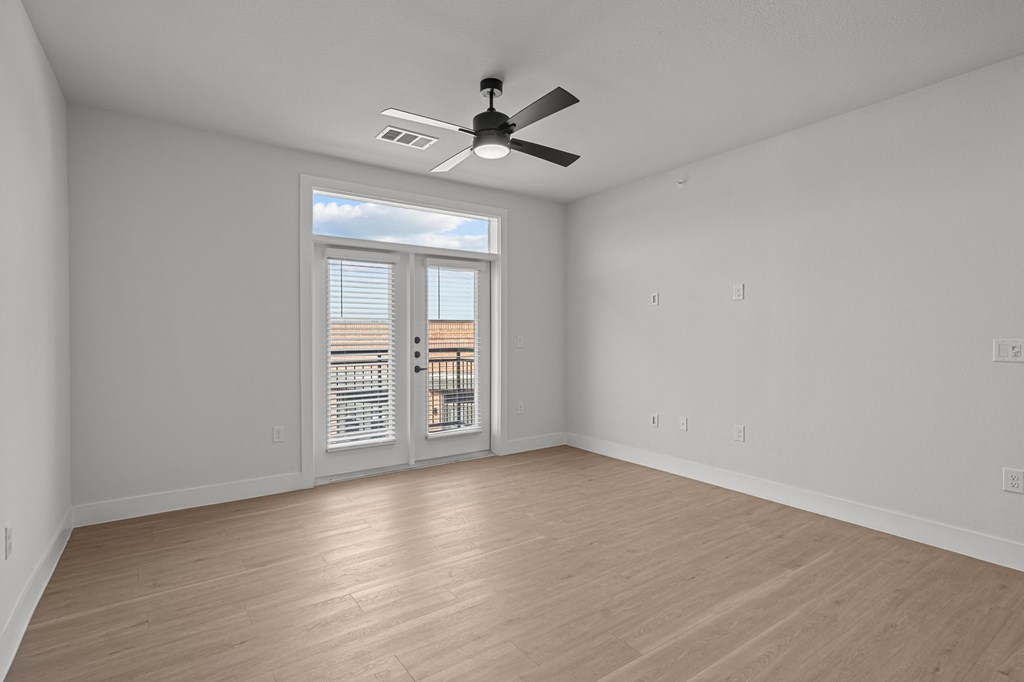 A room with a ceiling fan and a window with blinds.