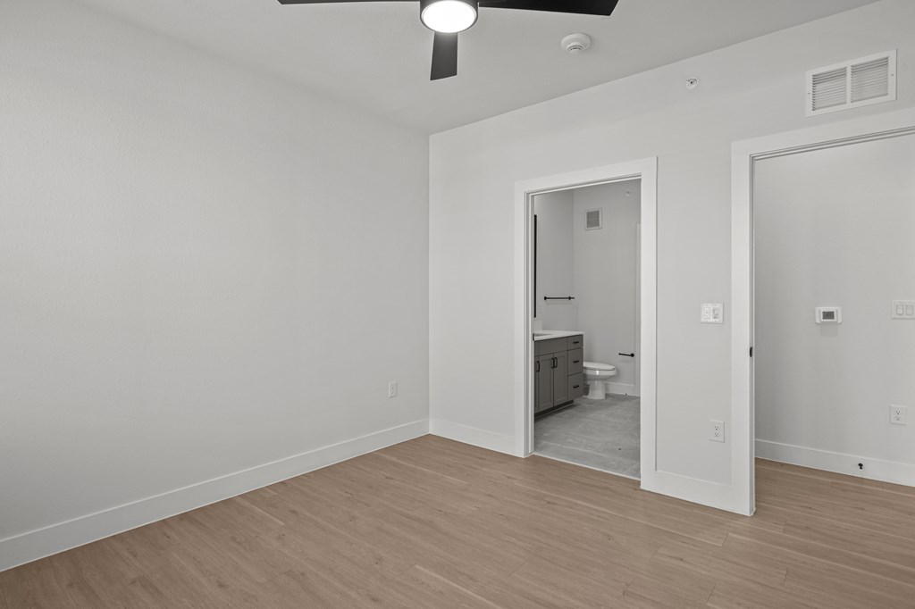 A room with a ceiling fan and a doorway leading to a bathroom.