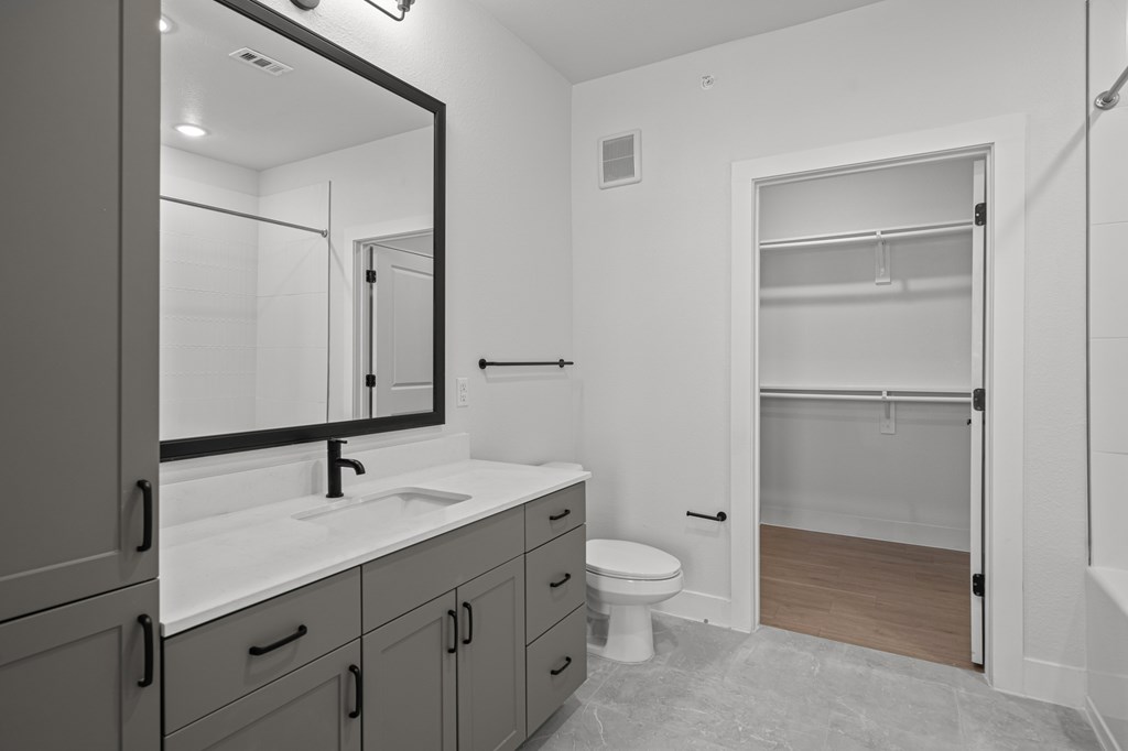 A bathroom with a sink, mirror, toilet and a walk in shower.