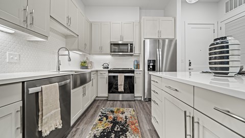 A modern kitchen with white cabinets and a black refrigerator.