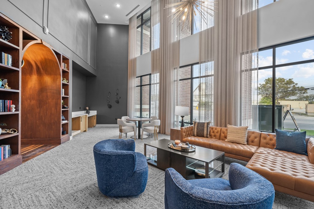 A modern living room with a large window and a brown leather couch.