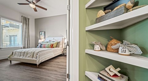A bedroom with a bed and a shelf with decorative items.