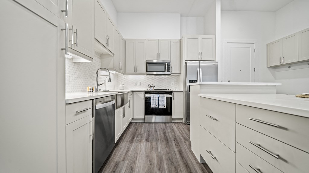 an all white kitchen with stainless steel appliances and white cabinets