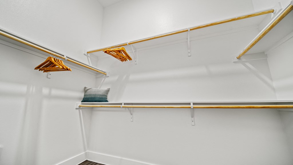 a walk in closet with white walls and a shelf with hanging lights