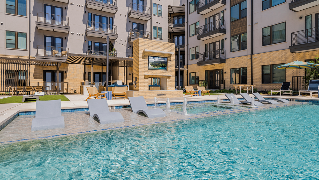 a swimming pool with lounge chairs in front of an apartment building