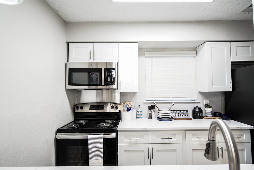 a white kitchen with black appliances and white cabinets