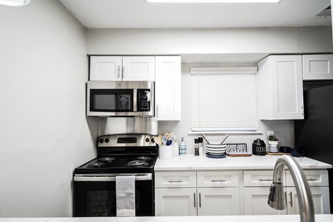 a white kitchen with black appliances and white cabinets
