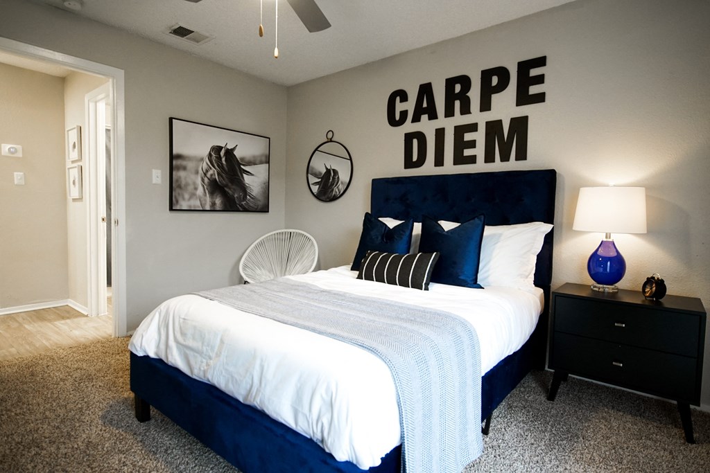 a bedroom with a bed with a white comforter and blue pillows