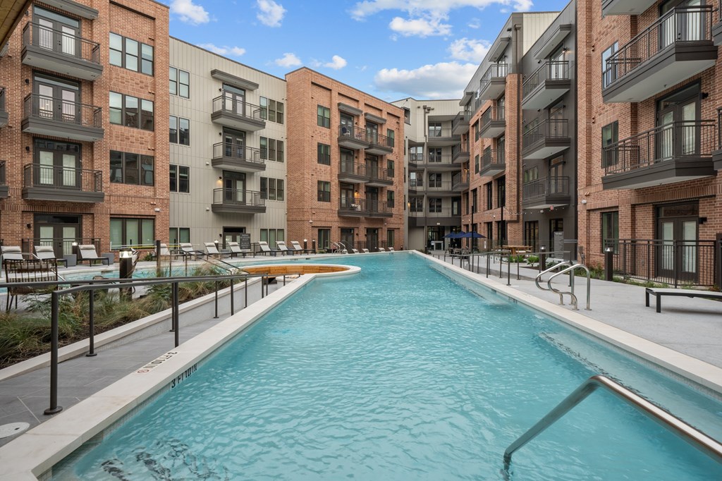A long rectangular pool in the middle of a courtyard surrounded by apartment buildings.