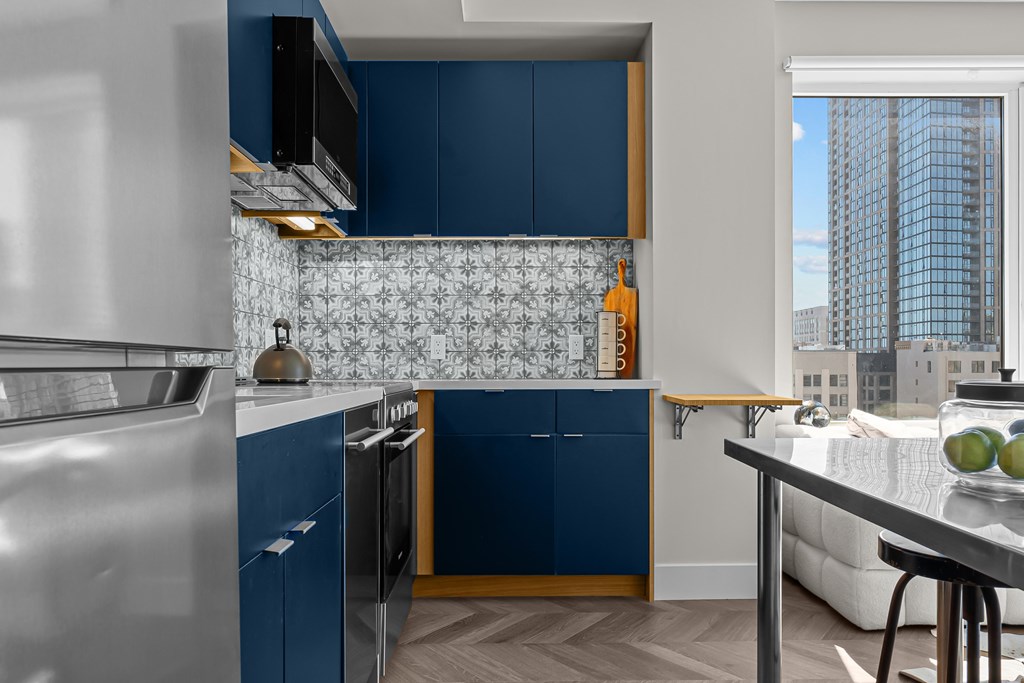 A kitchen with blue cabinets and a stainless steel refrigerator.