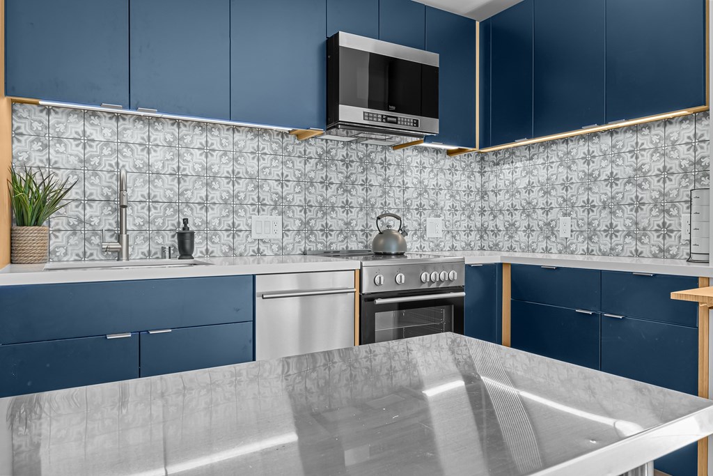 A kitchen with blue cabinets and a patterned backsplash.