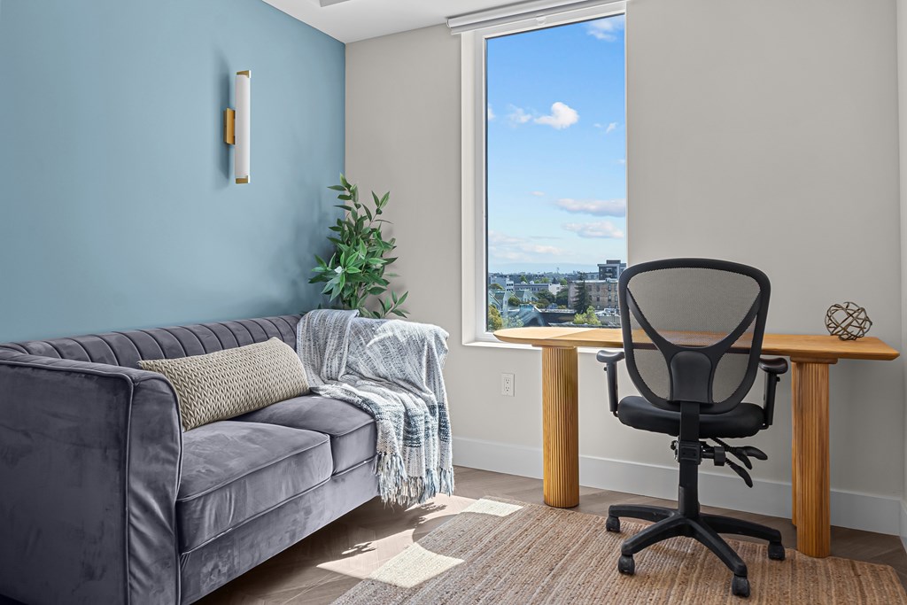 A grey couch with a pillow and blanket on it.