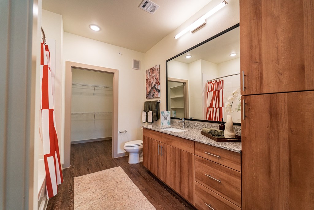 A bathroom with a toilet, sink, and mirror.
