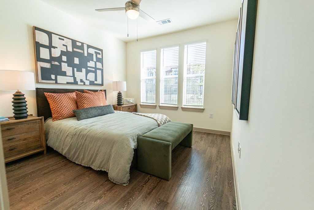 A bedroom with a bed, a bench, and a painting on the wall.