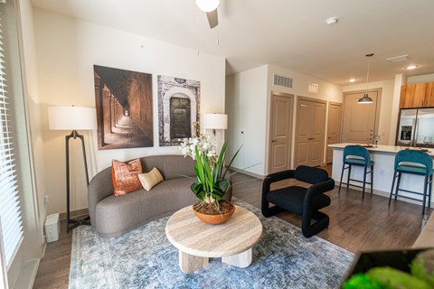 A living room with a grey couch, a wooden coffee table, and a painting on the wall.