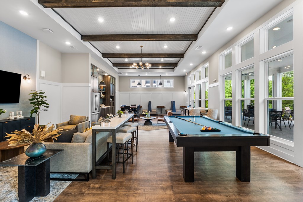 A pool table is in the middle of a room with a bar and a TV.